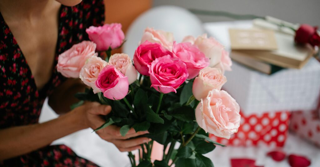 A close-up of a woman holding a bouquet of vibrant pink roses, symbolizing beauty and elegance.