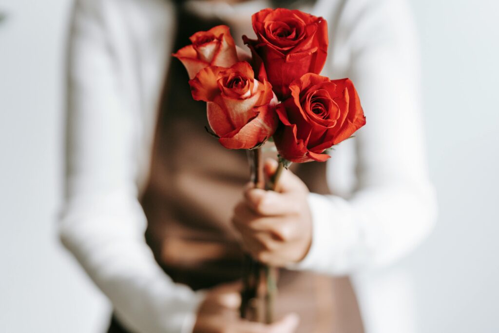 A close-up of a florist holding a bouquet of vibrant red roses, perfect for any occasion.