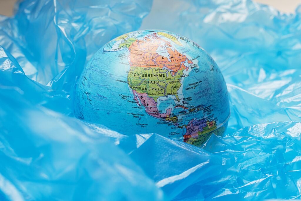 A globe surrounded by blue plastic represents global environmental issues and pollution.