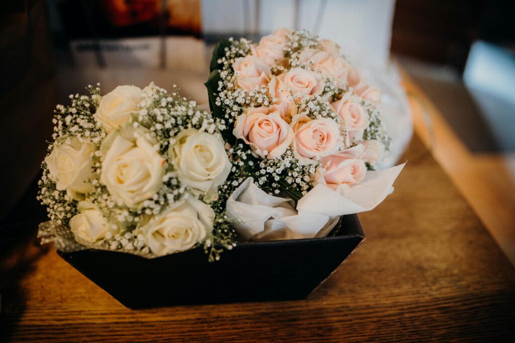 Two beautifully arranged rose bouquets with delicate baby's breath in a wooden box.