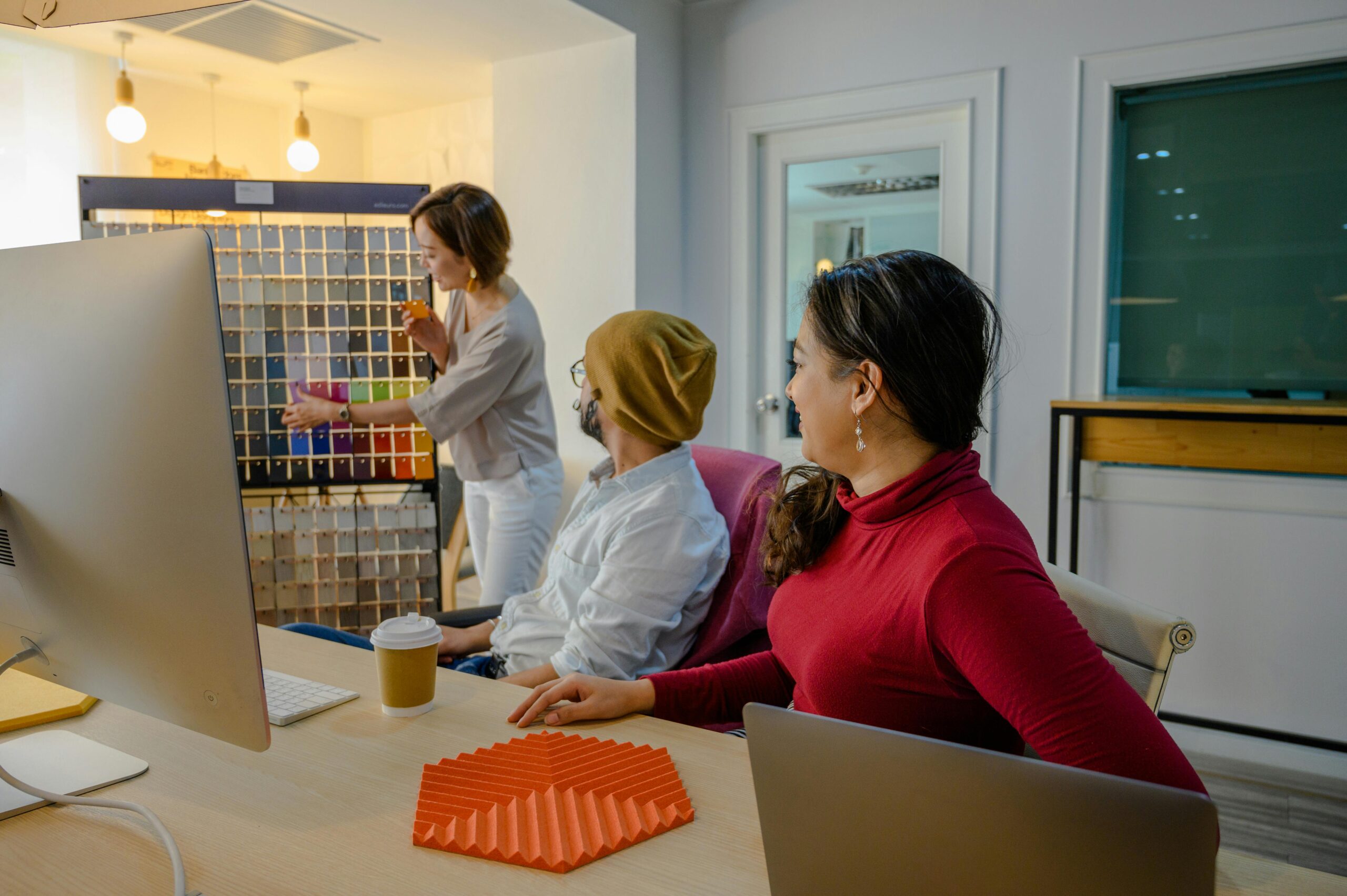 Group of coworkers discussing color samples in a bright, modern office setting.