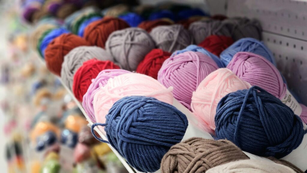 Vibrant yarn balls in a variety of colors neatly arranged on a store shelf.