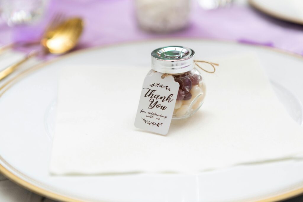 Close-up of a small glass jar with a thank you tag placed on a plate, perfect for weddings or events.