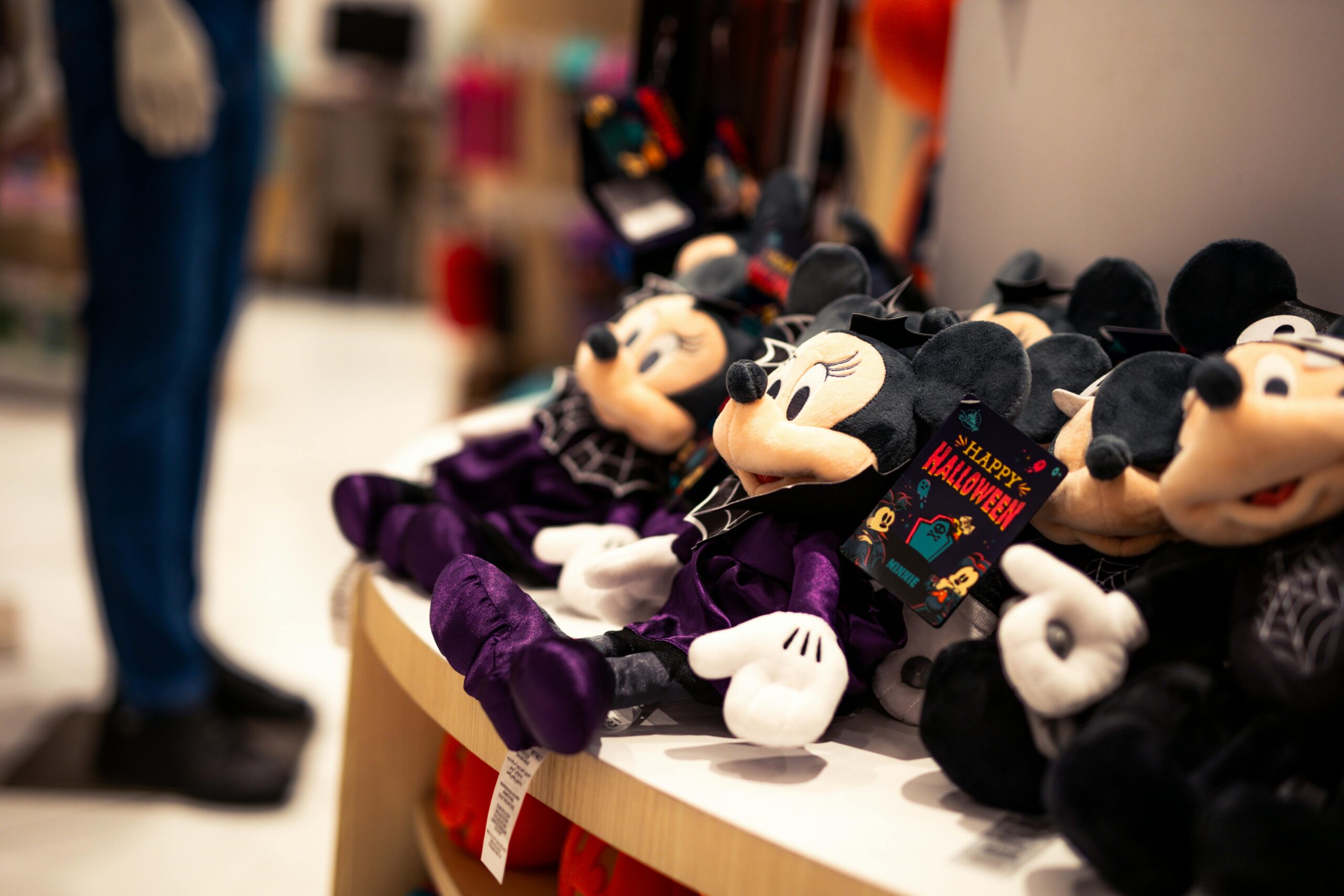Close-up of Halloween-themed Minnie Mouse plush toys in a store setting, perfect for festive decor.